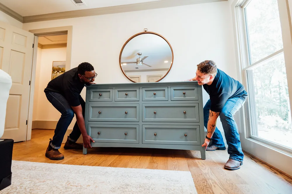Two LoadUp Loaders lifting a blue-gray dresser off the floor in a bright bedroom