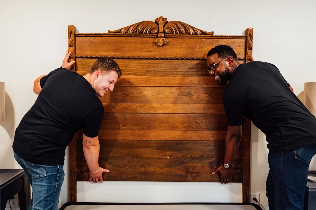 Two LoadUp Loaders lifting an ornate wooden bed frame headboard