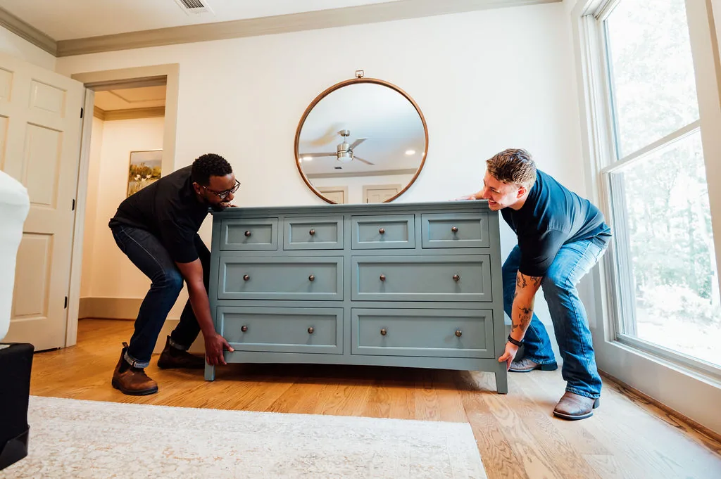 Two LoadUp Loaders lifting a blue-gray six-drawer dresser in a bedroom