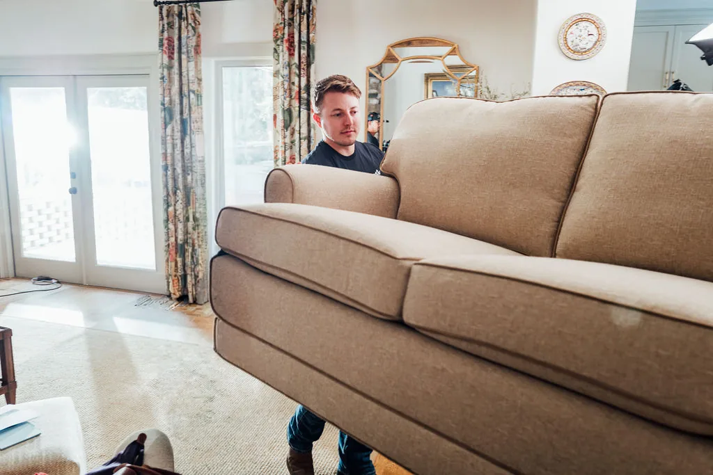 A LoadUp Loader carrying a large beige sofa out through a living room