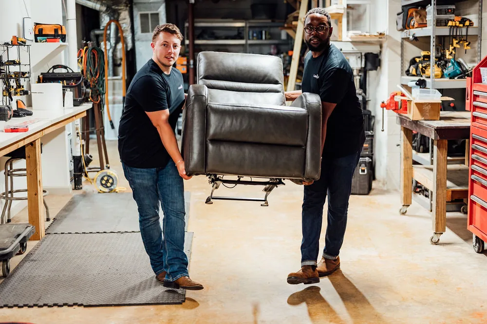 Two Furniture Disposal Plus Loaders carrying a tall wardrobe out of a home
