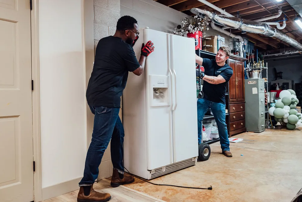 Two Furniture Disposal Plus Loaders removing a refrigerator from a kitchen